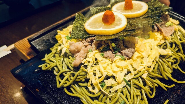 Kawara soba avec cha soba, bœuf, kinshi tamago, citron et nori sur une tuile chauffée