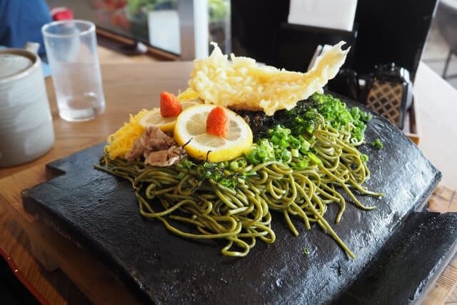 Kawara soba avec tempura, citron et oignon vert sur une tuile sombre