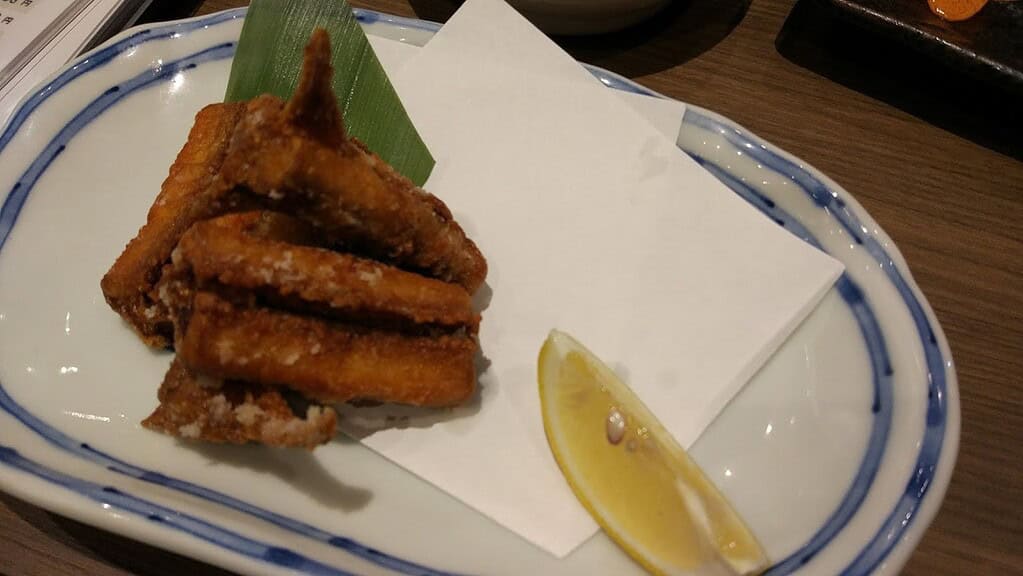Crispy fried chicken wings with lemon wedge, traditional Japanese cuisine, popular food in Japan, savory snack.