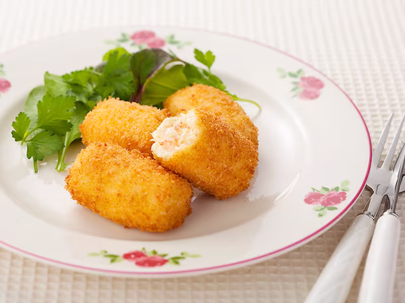 Crab cream croquette cut open to show creamy béchamel and crab filling