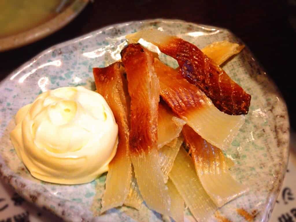 Grilled eihire (fish fins) served with a side of mayonnaise, showcasing Japanese seafood delicacy.