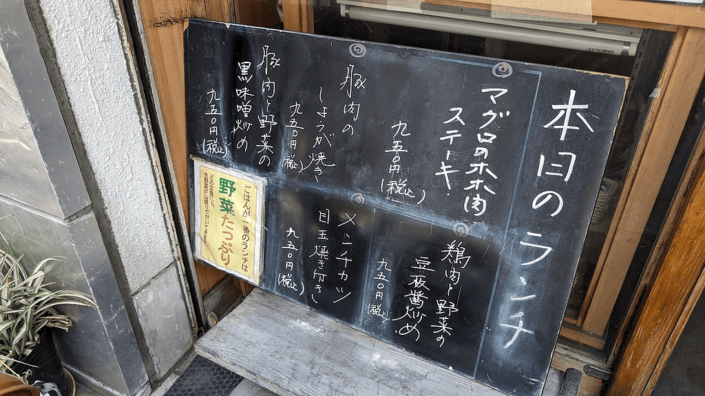 Japanese restaurant menu board with handwritten dishes and prices.