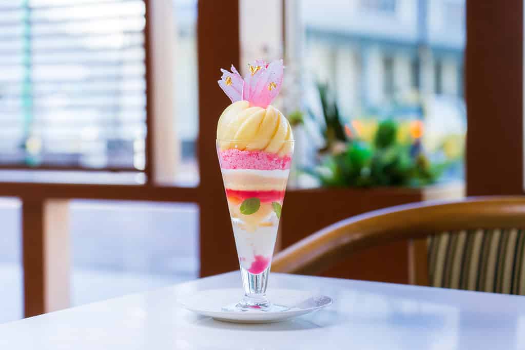 Elegant Japanese parfait with colorful layers and floral decoration.