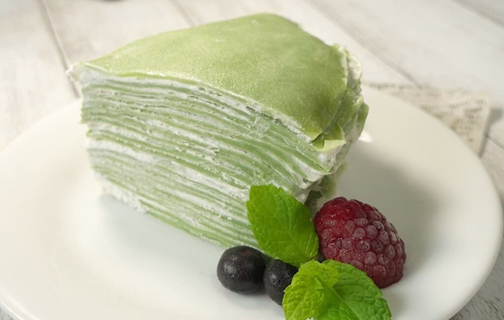 Delicious green tea Mille Crepes with fresh berries and mint garnish, showcasing popular Japanese de.