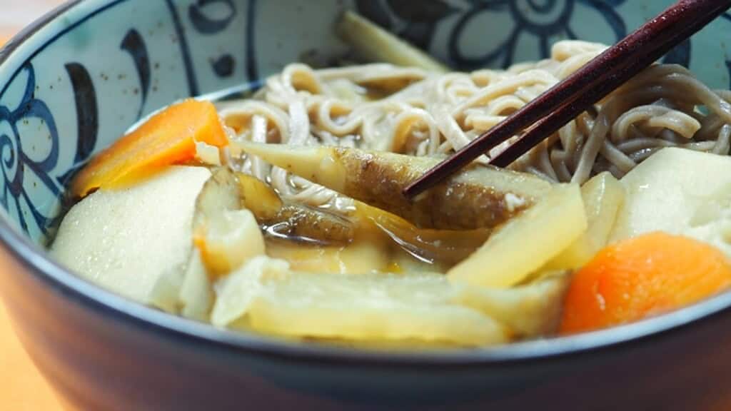 Traditional Kenchin Soba with vegetables in a ceramic bowl.