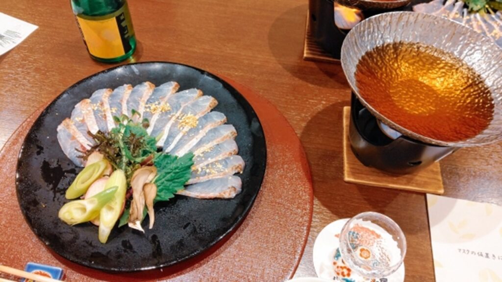 Nodoguro sashimi served with fresh garnishes on a black plate in Japan.