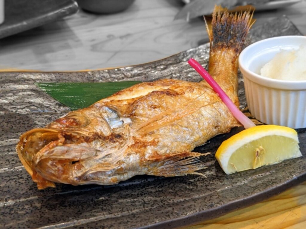 Grilled nodoguro fish served with lemon and side dish in Japan.