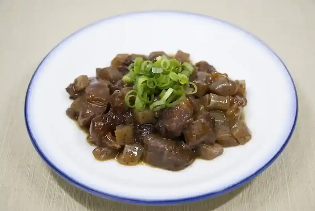 Traditional Kobe Bokkake beef stew with green onions on a white plate.