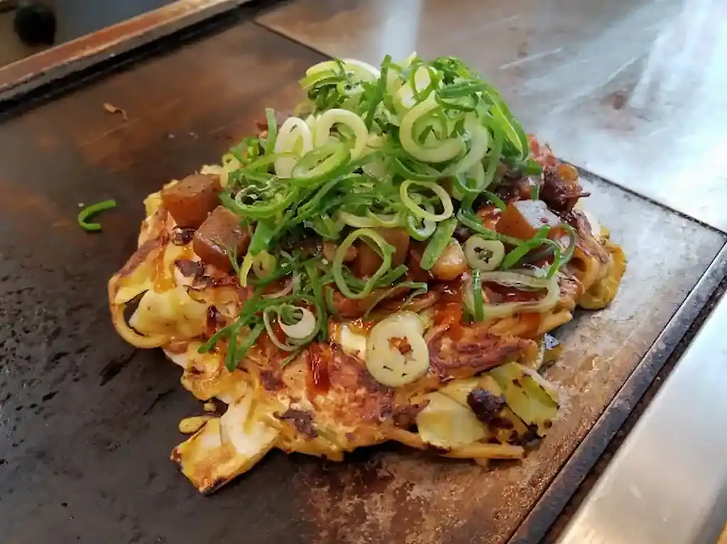 Delicious Kobe Bokkake topped with green onions, served on a hot griddle in Japan.