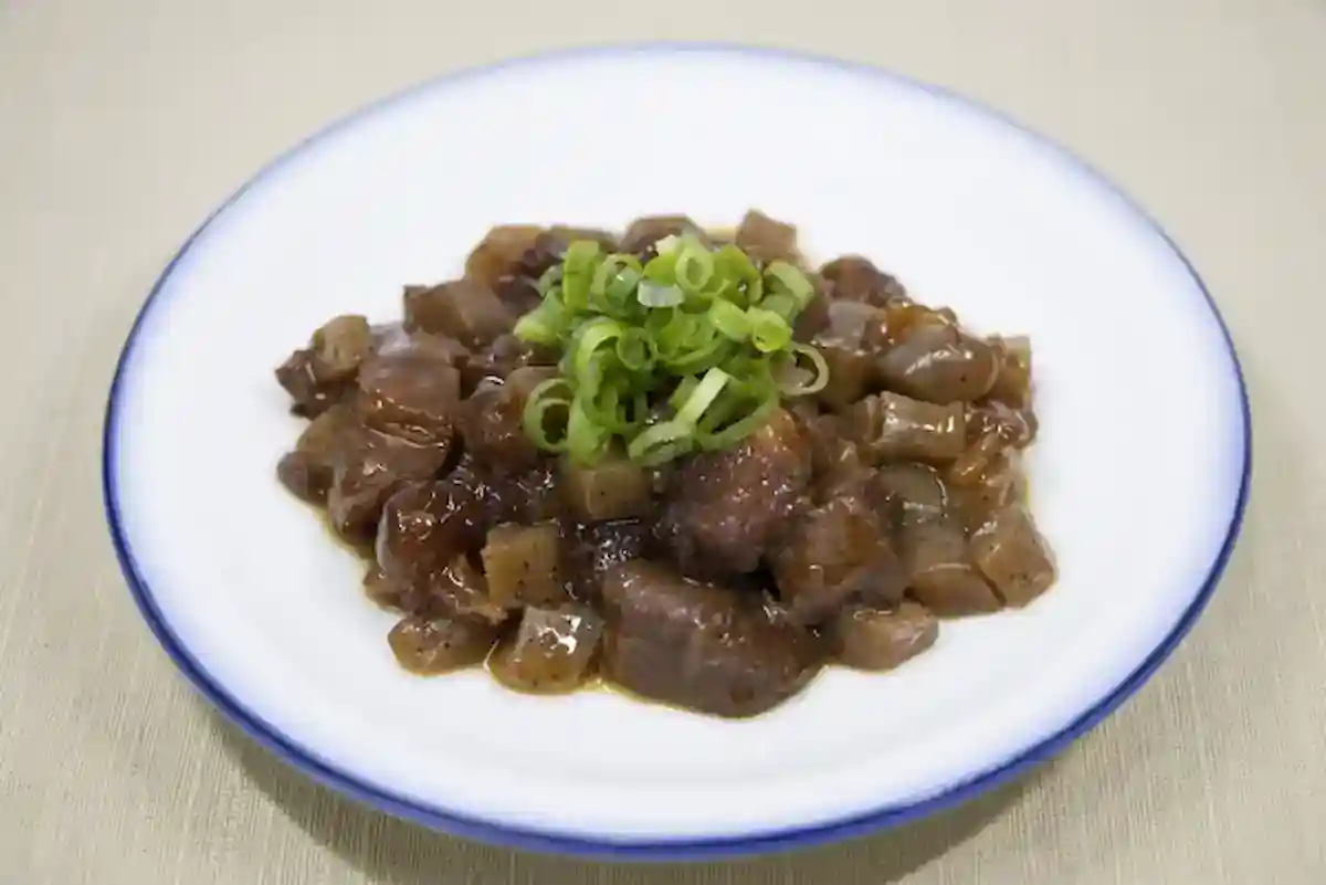 Traditional Kobe Bokkake beef stew with green onions on a white plate.