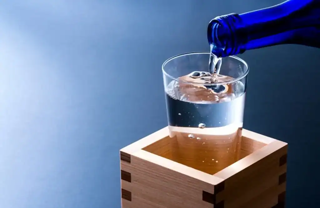 Pouring Nada Gogo Sake into a glass, showcasing Japanese sake culture.