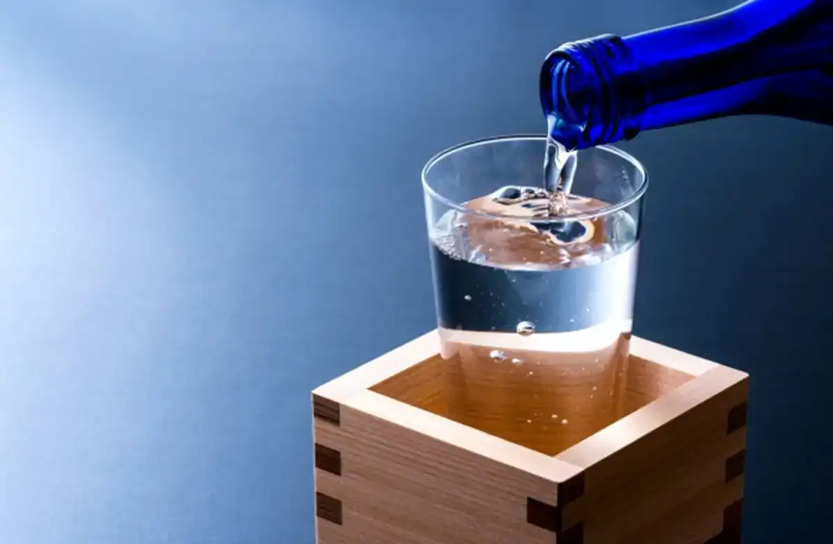 Pouring Nada Gogo Sake into a glass, showcasing Japanese sake culture.