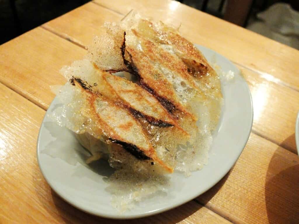 Delicious Kobe miso gyoza with crispy exterior and savory filling, served on a white plate.
