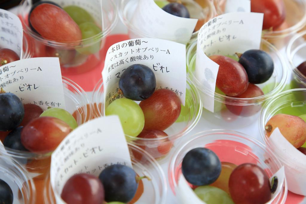 Fresh Shine Muscat grapes in small cups, showcasing their vibrant green and purple colors.