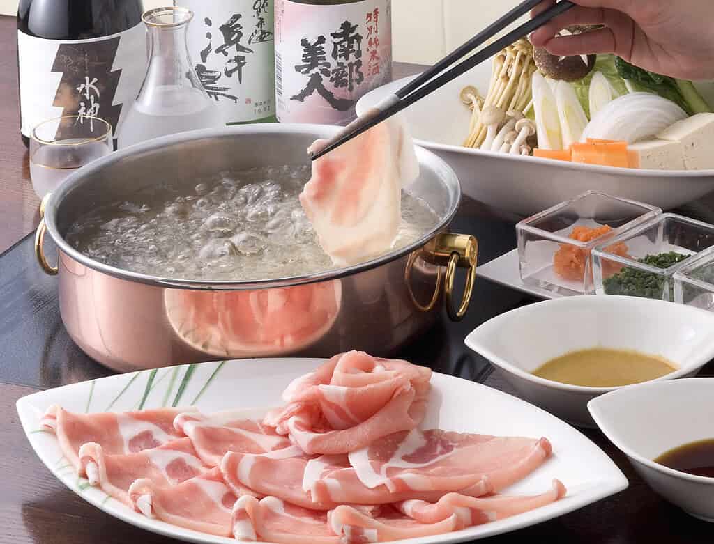 Thinly sliced Maesawa Beef being cooked in hot pot, ready for shabu-shabu. Premium Japanese beef for.