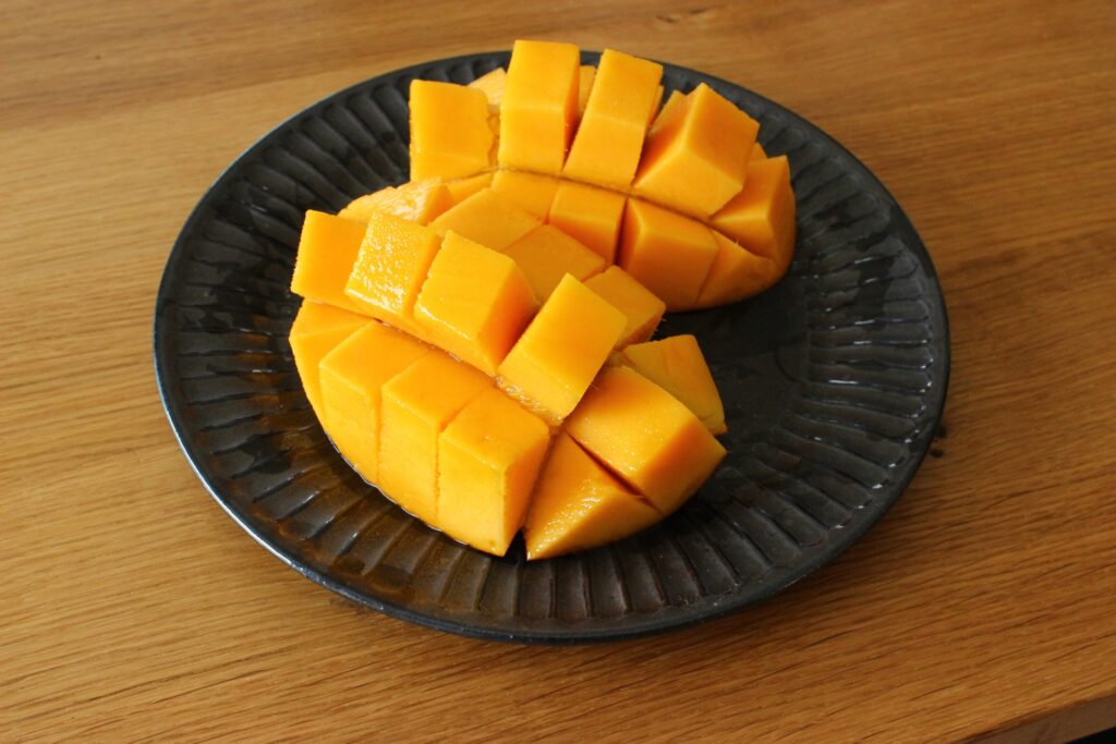 Freshly sliced ripe mango on a black plate, ready to serve.