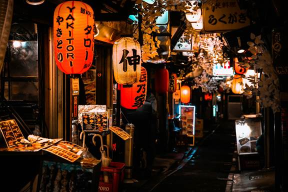 Traditional Japanese street scene with lanterns and small shops at night.