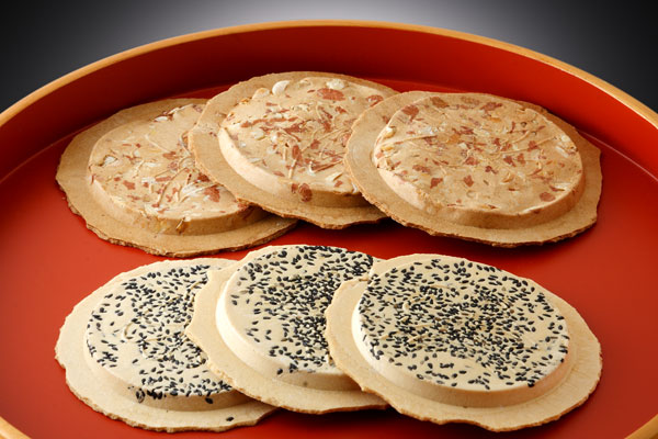 Traditional Japanese rice crackers with black and white sesame seeds on a red tray.