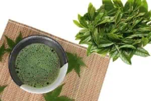 Culinary Matcha Fresh green matcha tea with tea leaves on a bamboo mat.