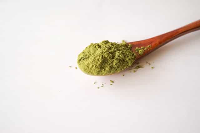 Fine powdered matcha green tea on a wooden spoon for Japanese tea ceremonies.