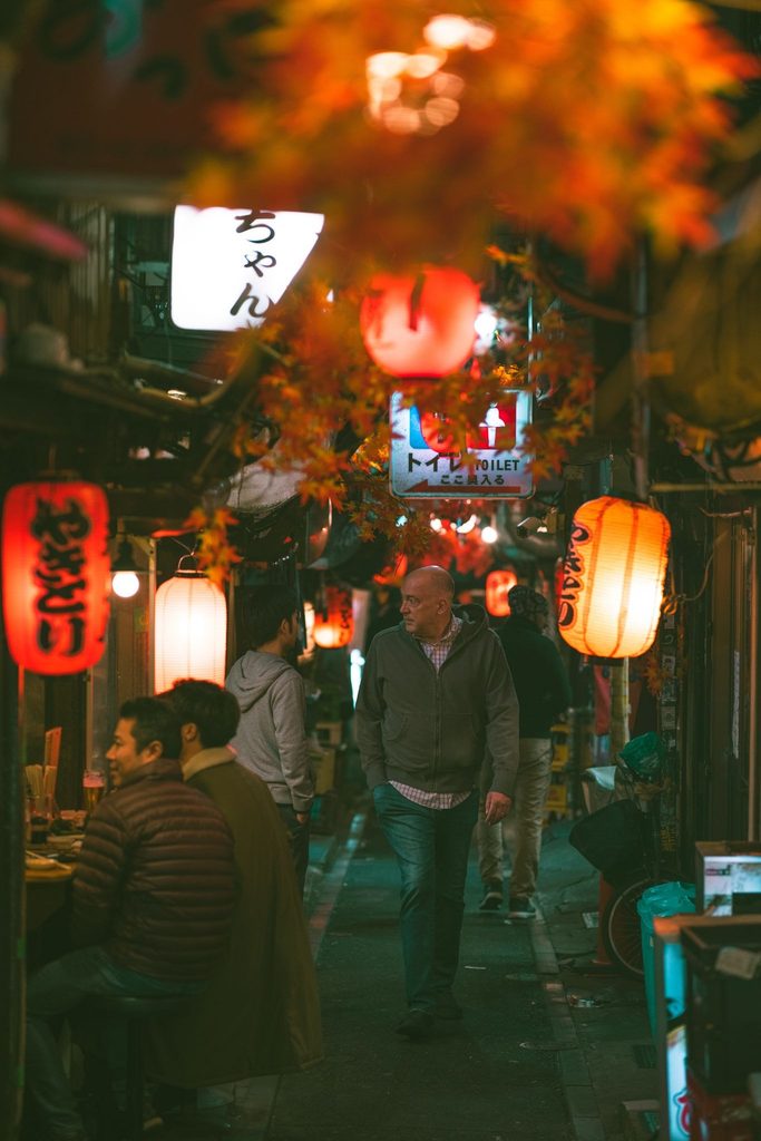 Vibrant street scene in Japan with lanterns and people at night.