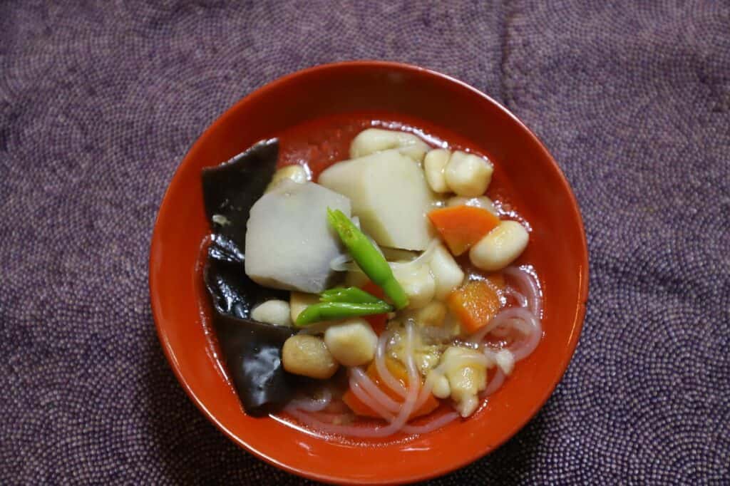 Kozuyu soup with vegetables and tofu in a red bowl.