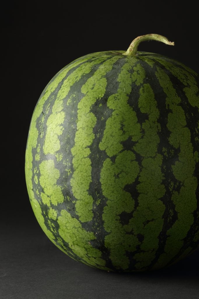 Obanazawa watermelon with green and dark green striped pattern on black background.