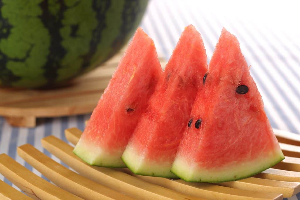 Fresh slices of Obanazawa watermelon on a bamboo mat.