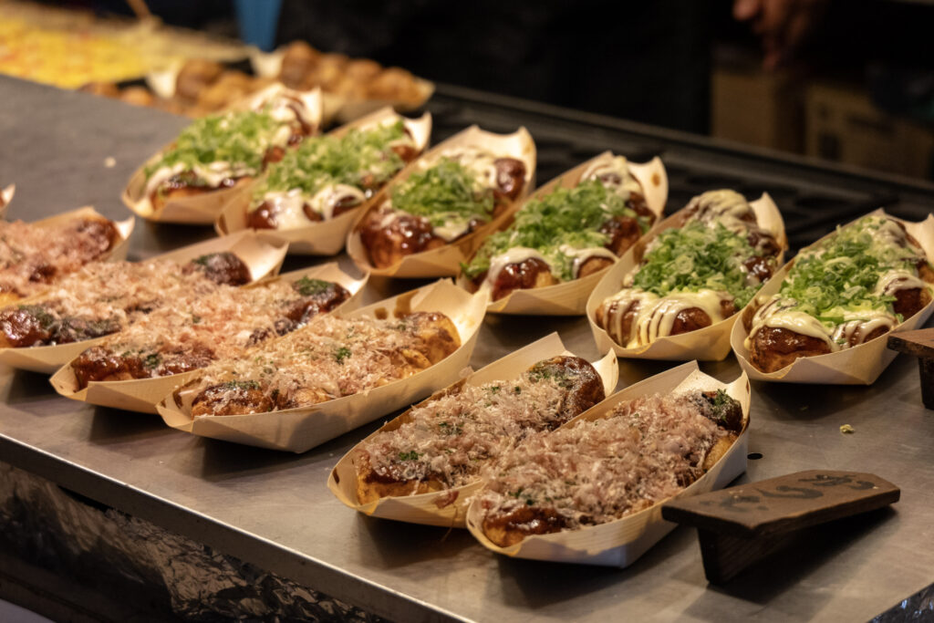 Assorted Japanese street food snacks with toppings and sauces.