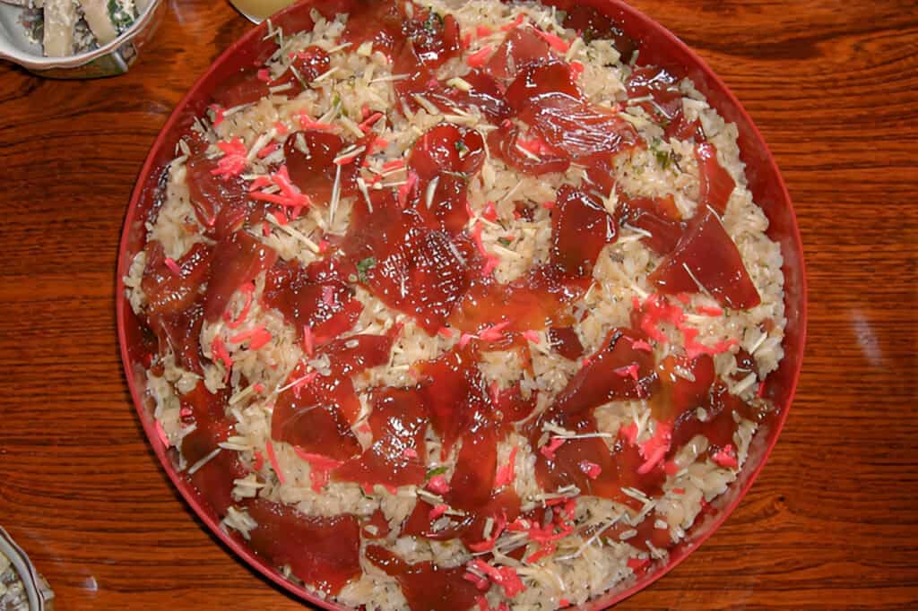 Traditional Japanese Tekonezushi with sashimi and rice in a red bowl.
