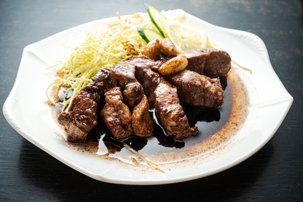Yokkaichi Tonteki with grilled pork and cabbage on a white plate.
