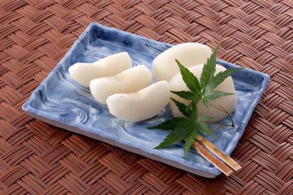 Kureha Nashi pear slices on a blue ceramic plate with a green leaf garnish.