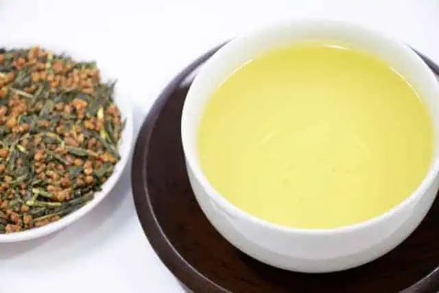 Cup of genmaicha tea with roasted rice on side, traditional Japanese beverage.