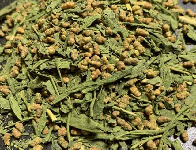 Close-up of genmaicha tea with green tea leaves and roasted rice grains.