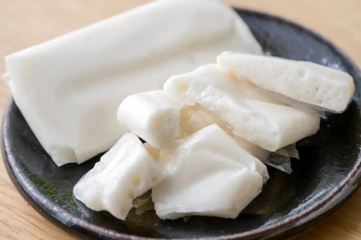 Three bars of amegata wrapped in thin edible film on a dark lacquered plate