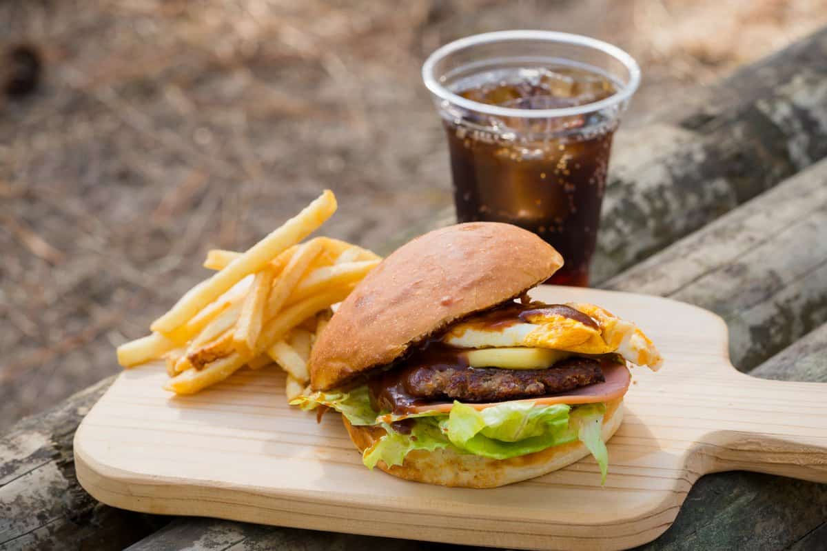 A Karatsu Burger on a wooden board with french fries and a cola