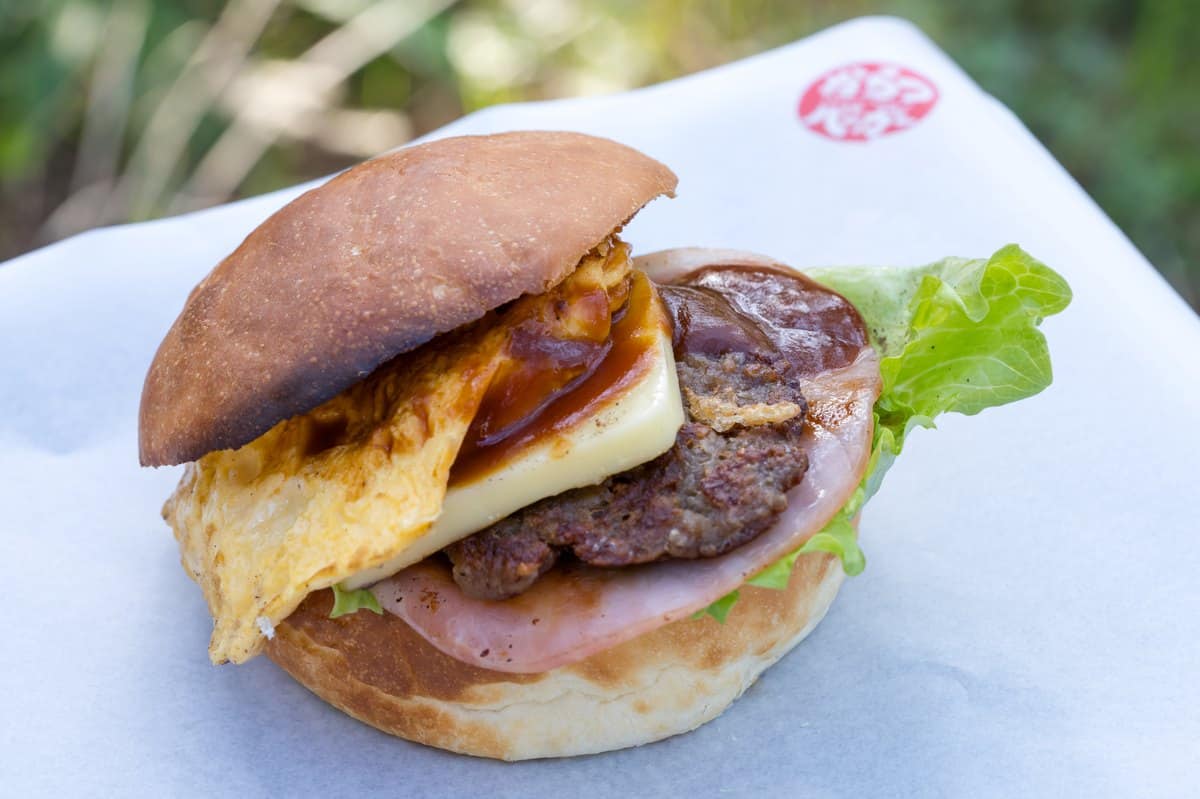A Karatsu Burger opened on white paper showing egg, cheese, patty, ham and lettuce
