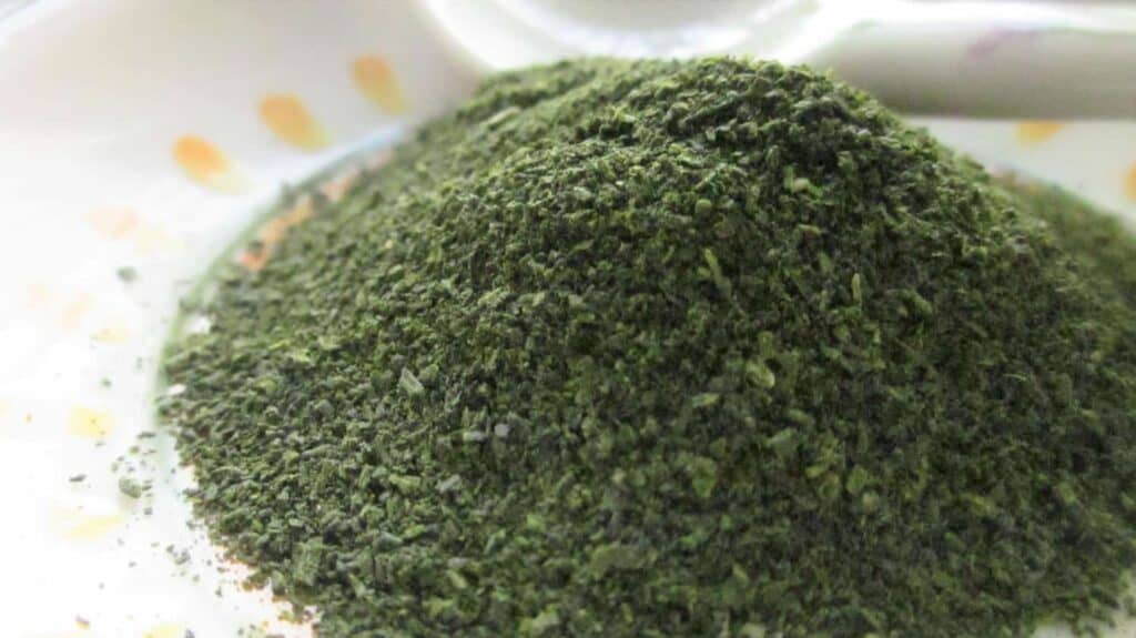 Konacha, fine dark green particles of Japanese green tea, piled on a small white dish