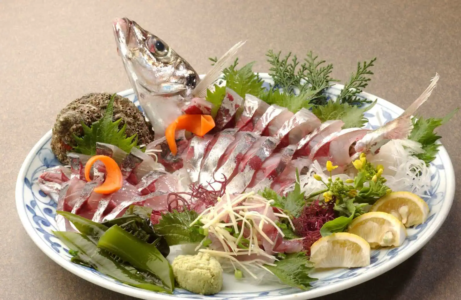 Sekiaji sashimi platter with sliced Seki horse mackerel, shiso leaves, shredded ginger, wasabi, lemon wedges and seaweed