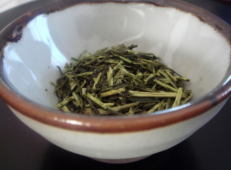 A small ceramic bowl of shiraore, a Japanese green stem tea with pale, flat tea stems mixed with dark green leaf pieces